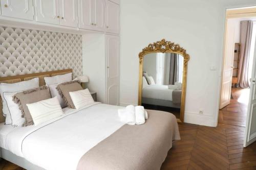 une chambre avec un grand lit blanc et un miroir dans l'établissement Charming 3 bedroom Haussmannien apartment in 17th, à Paris