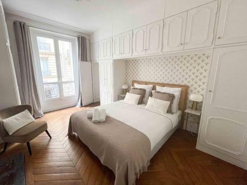une chambre blanche avec un grand lit et une chaise dans l'établissement Charming 3 bedroom Haussmannien apartment in 17th, à Paris
