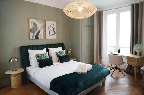 - une chambre avec un grand lit, un bureau et un lustre dans l'établissement Charming 3 bedroom Haussmannien apartment in 17th, à Paris