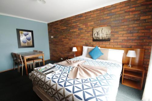 a bedroom with a bed and a brick wall at Golden Palms Motel in Geelong