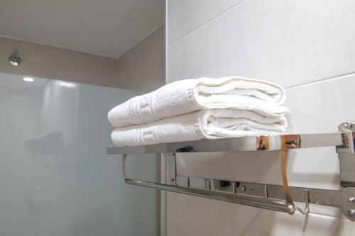 a pile of towels on a towel rack in a bathroom at L'Oncle Pere Habitacions in L'Alcúdia