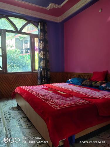 a bedroom with a bed with a red blanket and a window at Pineview Hostel and Cafe in Kasol
