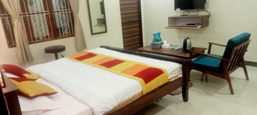 a bedroom with a desk and a bed and a chair at Redstone House by Oxystays Hospitality in Ganpatipule