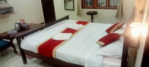 a large bed in a room with a desk at Redstone House by Oxystays Hospitality in Ganpatipule