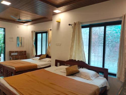 a bedroom with two beds and a large window at Redstone House by Oxystays Hospitality in Ganpatipule