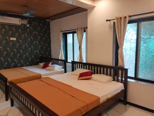 two beds in a room with two windows at Redstone House by Oxystays Hospitality in Ganpatipule
