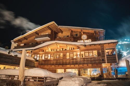 a large wooden building with snow on it at Alpin Juwel - Bio und Lifestylehotel in Saalbach Hinterglemm