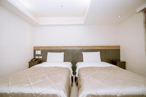 two beds sitting next to each other in a room at Guide Hotel Taoyuan Fuxing in Taoyuan