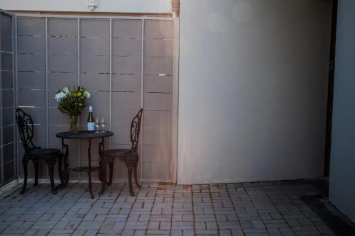 a table with two chairs and a vase with flowers at Marilyn's Rooms in Swellendam