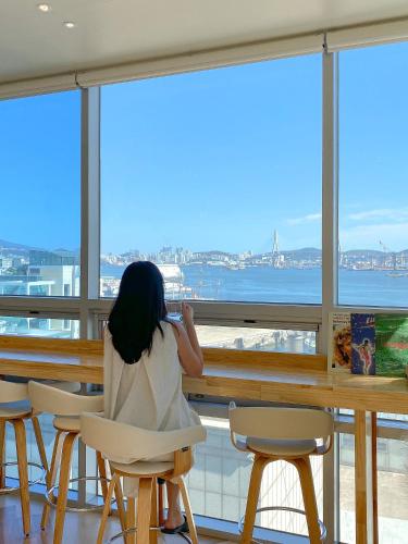 Eine Frau, die am Tisch sitzt und aus dem Fenster schaut. in der Unterkunft Stay Gaon in Busan