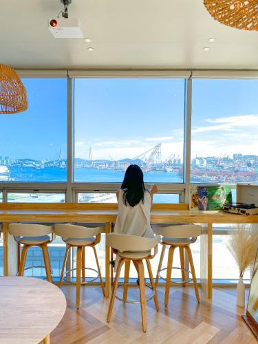 een vrouw aan een tafel die uitkijkt op de oceaan bij Stay Gaon in Busan