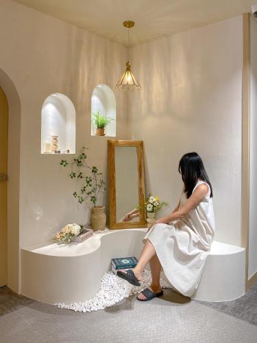 a woman sitting on a counter in front of a mirror at Stay Gaon in Busan