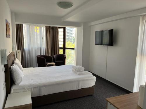 a hotel room with a bed and a flat screen tv at Acomodoro Residence in Bucharest