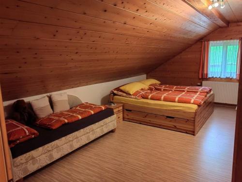 two beds in a room with wooden walls at Ferienwohnung Ingrid in Radmer an der Hasel
