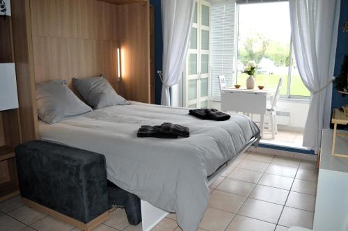 a bedroom with a large bed and a large window at Le Petit Matelot, studio fonctionnel avec loggia in Courseulles-sur-Mer