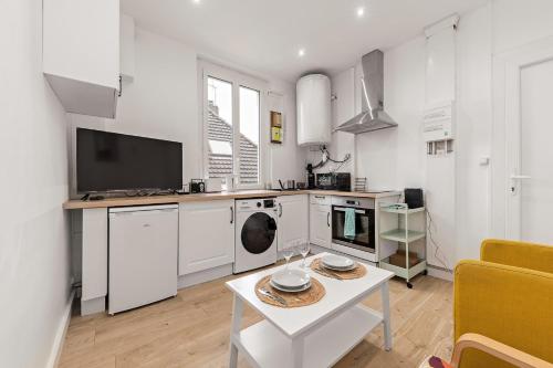 a kitchen with white appliances and a table in a room at L'Etape Relax in Saint-Étienne-du-Rouvray