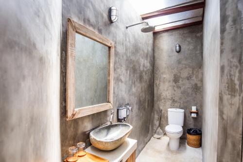a bathroom with a sink and a toilet and a mirror at Pachamama Canggu Bali in Canggu