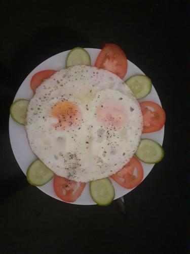 a fried egg on a plate with tomatoes and cucumbers at Hoan Chau Homestay in Phong Nha
