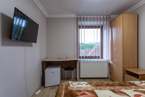 a room with a bed and a desk and a television at Hotel Intourist in Mukacheve