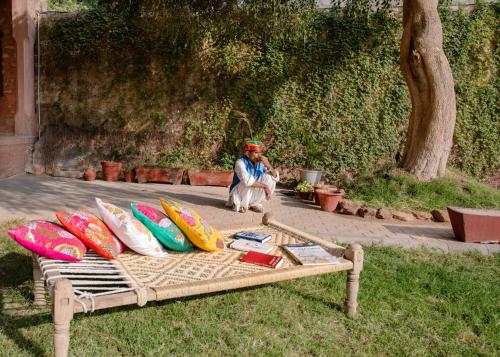 a man sitting next to a bench with surfboards on it at Kot Dunara - A 16th Century Castle near Jodhpur in Jodhpur