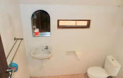 a white bathroom with a toilet and a sink at Surf Garden Lombok in Bumbang