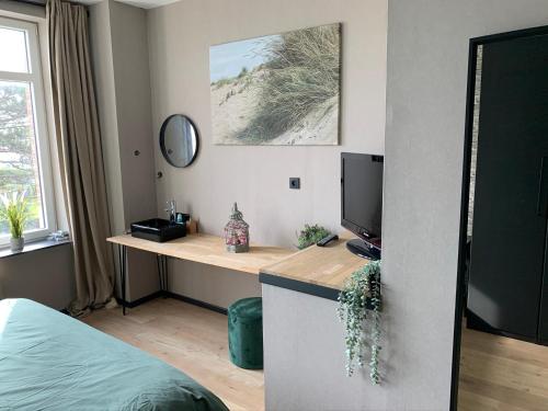 1 dormitorio con escritorio, TV y cama en loftlivinq@sea, en Middelkerke