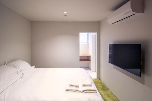 a bedroom with a white bed and a flat screen tv at Akizuki OKO art&inn in Asakura