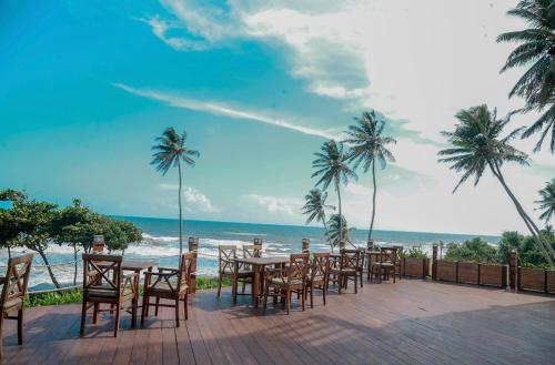 a patio with tables and chairs on the beach at Oceanfront Condos Galle-Apartment L410 A in Galle