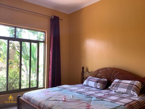 a bedroom with a bed and a large window at Pleasant Rusororo in Kigali