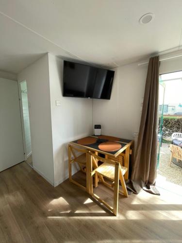 a room with a table and a tv on a wall at Camping des Acacias in Saint-Paulet-de-Caisson