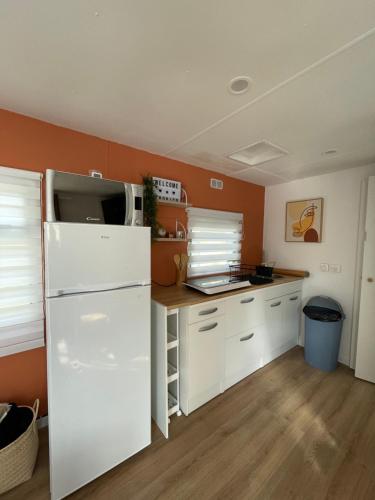 a kitchen with white cabinets and a white refrigerator at Camping des Acacias in Saint-Paulet-de-Caisson