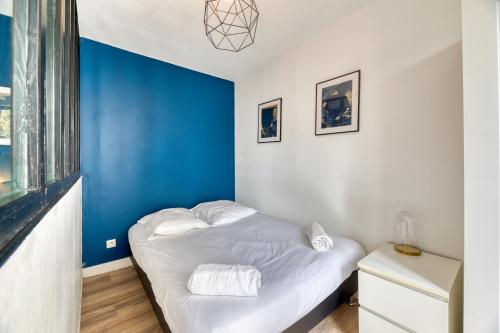 Cette chambre dispose d'un lit avec un mur bleu. dans l'établissement Le BlueArt, votre logement au cœur de Rouen, à Rouen