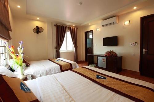 a hotel room with two beds and a television at TD Luxury Hotel in Cat Ba
