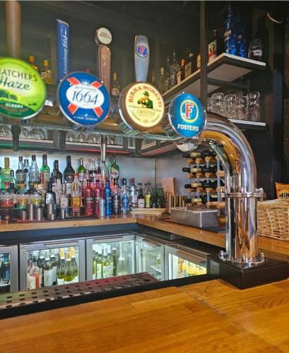 a bar with a counter with bottles of alcohol at Dog and Partridge Inn in Calne