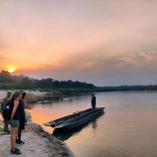 a man is standing in a boat in the water at BhupuSainik Guest House - Sauraha, Chitwan in Sauraha