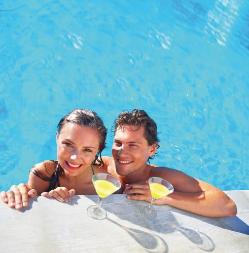 a man and a woman holding wine glasses in a swimming pool at Dik Dik Hotel in Arusha