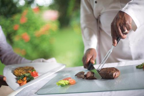 a person cutting meat on a table with a knife at Dik Dik Hotel in Arusha