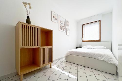 - une chambre blanche avec un lit et une armoire en bois dans l'établissement Appart T2 proche commerces et NAVAL GROUP, à Cherbourg en Cotentin