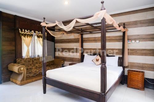 a bedroom with a canopy bed and a chair at Kebon Krapyak Cottage Syariah Mitra RedDoorz near Stadion Maguwoharjo in Yogyakarta