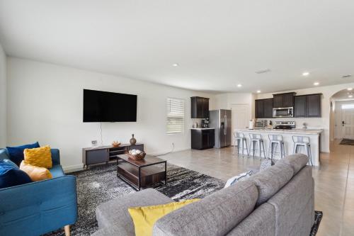 un salon avec un canapé et une cuisine dans l'établissement Brand New 4-Bedroom House near Disney & Beaches!, à Port Sainte-Lucie