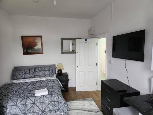 a bedroom with a bed and a flat screen tv at Double room in Stone in Kent