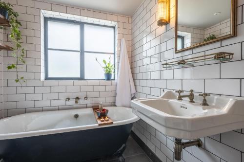 a white bathroom with a tub and a sink at Granary Cottage in Wenhaston