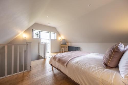 a bedroom with a large white bed in a attic at Granary Cottage in Wenhaston