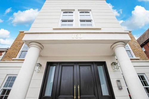 a white building with a black front door at 2BR Urban Vista Retreat CHCL F7 in Chigwell