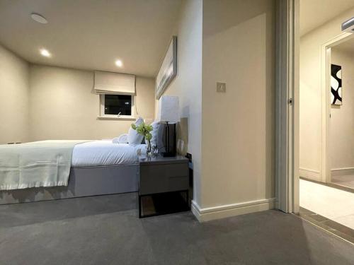 a bedroom with a bed and a table with flowers on it at 2BR Urban Vista Retreat CHCL F7 in Chigwell