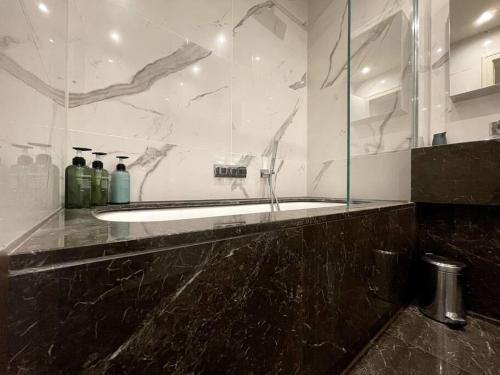 een badkamer met een bad en een glazen douche bij 2BR Urban Vista Retreat CHCL F7 in Chigwell