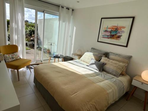 a bedroom with a bed and a chair and a window at Chambre d'Hôtes de la Grande Greve in Roscoff