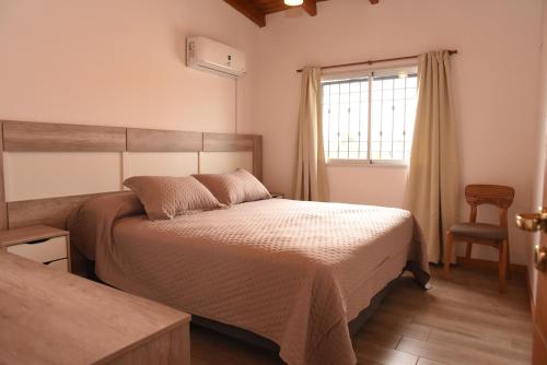 ein Schlafzimmer mit einem Bett, einem Fenster und einem Stuhl in der Unterkunft Cozy House in San Nicolás de los Arroyos