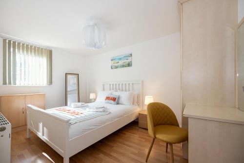 マンチェスターにあるWithington Apartmentsのベッドと椅子のある白い寝室