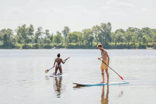 two men are standing on paddle boards in the water at Fries Vakantiehuis, grote tuin, nabij het Pikmeer in Grou